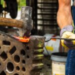 Operaio metalmeccanico al lavoro in officina, circondato da attrezzature e macchinari.